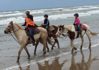 A horse rider and two children enjoying a horse ride by the seaside